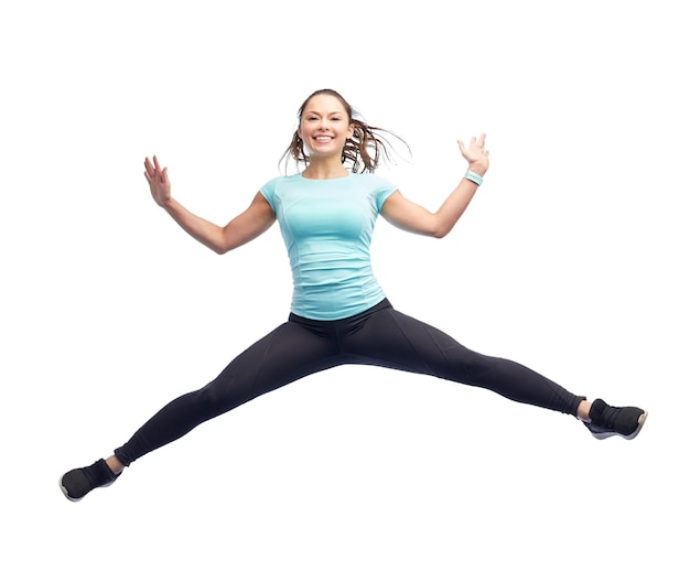 Photo sport, fitness, motion and people concept - happy smiling young woman jumping in air over white background