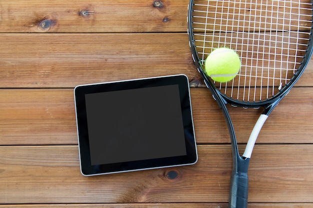 sport, fitness, technologie, spel en objecten concept - close-up van tennisracket met bal en tablet pc-computer op houten vloer