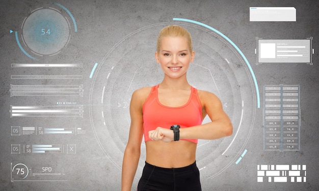 Foto concetto di sport, fitness e tecnologia: giovane donna sorridente felice con rilevatore di frequenza cardiaca o smartwatch su sfondo grigio cemento