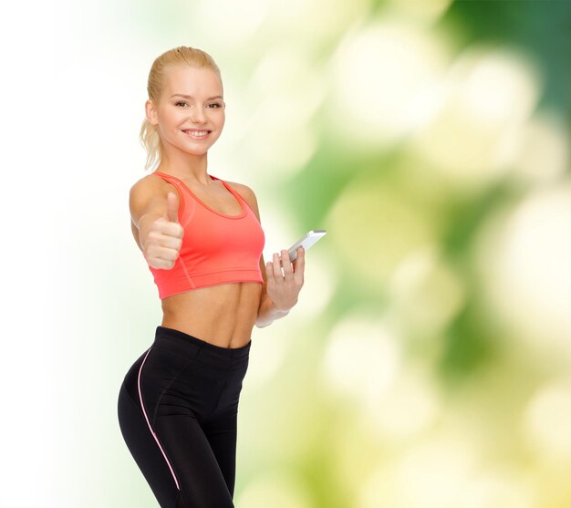 sport, fitness, technology, internet and healthcare concept - smiling sporty woman with smartphone showing thumbs up