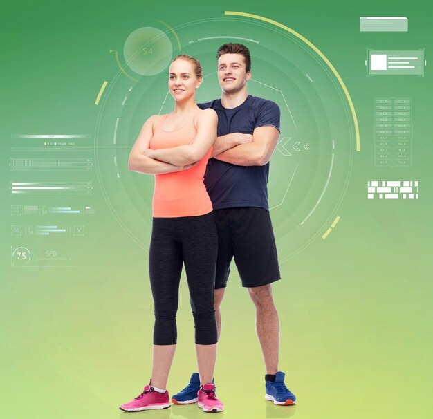 Sport, fitness, technology and people concept - happy sportive man and woman over green background