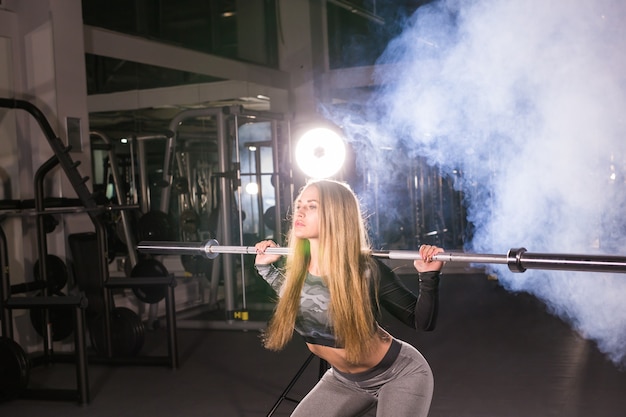концепция спорта, фитнеса, тренировок и счастья - спортивная женщина со штангой в тренажерном зале