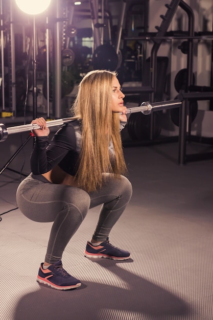 Sport, fitness, training and happiness concept - sporty woman with barbell in gym.