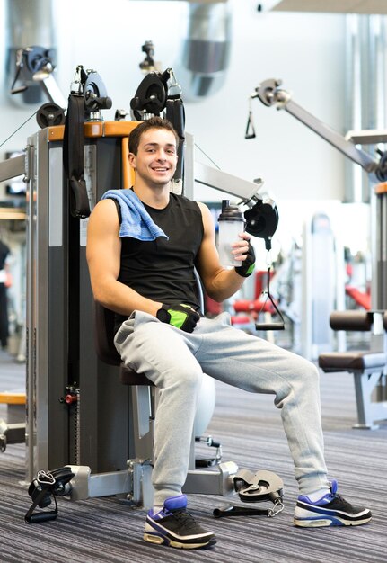 sport, fitness, uitrusting, levensstijl en mensenconcept - glimlachende man die op gymnastiekmachine uitoefent