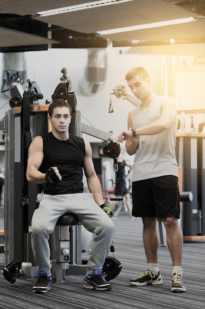 sport, fitness, uitrusting, levensstijl en mensenconcept - mannen oefenen op gymmachine