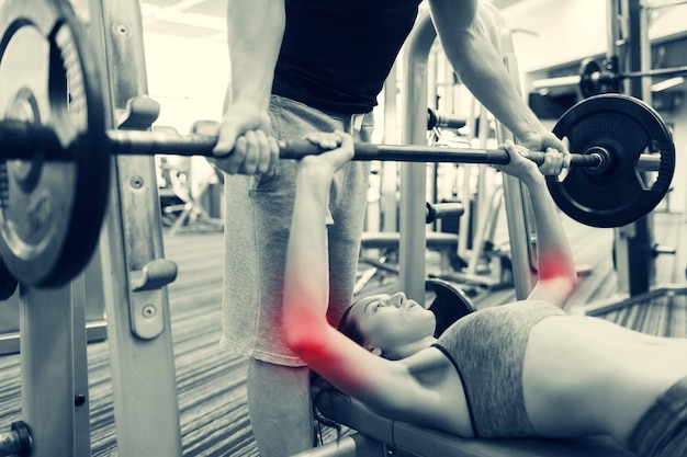 스포츠, 피트니스, 역도, 스포츠 부상 및 사람 개념 - 체육관에서 바벨을 구부리는 근육을 가진 젊은 여성 및 개인 트레이너