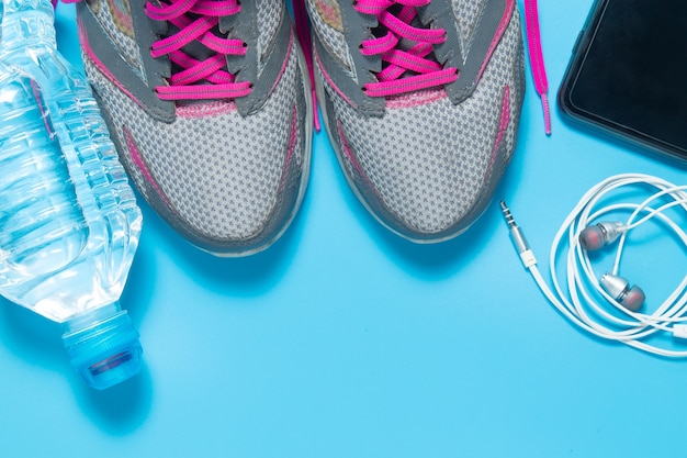 Sport flat lay shoes with water bottle, smartphone, earphones. 