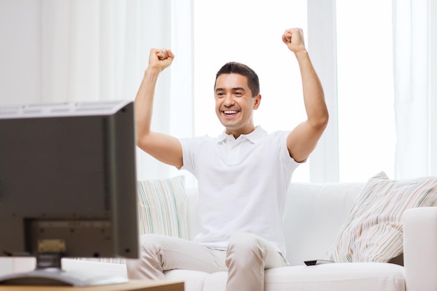 sport, geluk en mensen concept - lachende man kijken naar sport op tv en ondersteunend team thuis