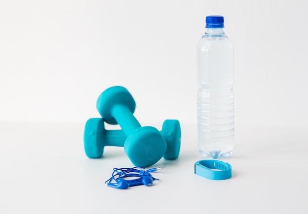 Sport, gezonde levensstijl en objecten concept - close-up van domoren, fitness tracker, oortelefoons en water fles op witte achtergrond