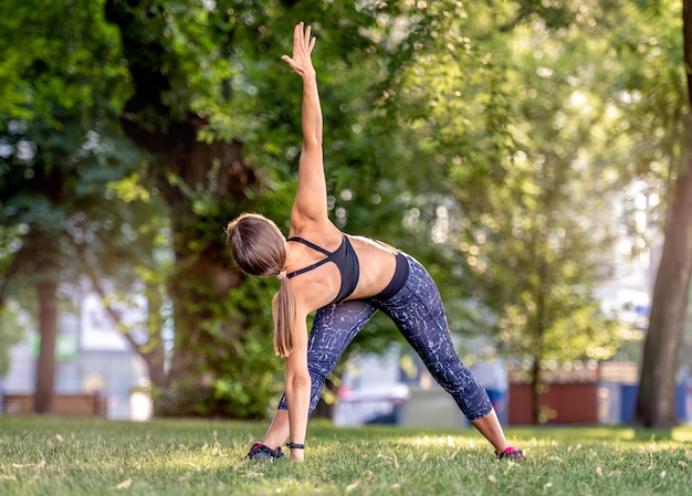 Ragazza sportiva che fa yoga in natura al mattino e in piedi in posa. giovane donna che si esercita e si allunga all'aperto