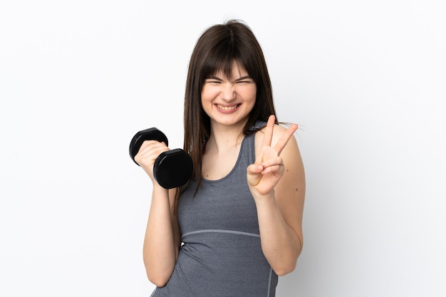 sport girl making weightlifting isolated on blue smiling and showing victory sign