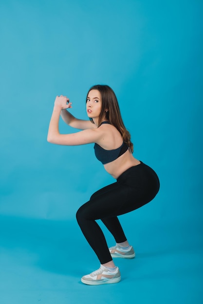 sport girl performs workout on blue background