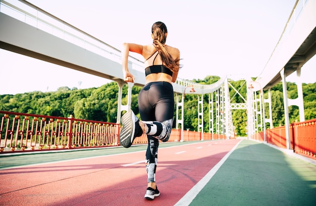 Sport and health lifestyle. Back view shot of Running young woman in sport clothes outdoors