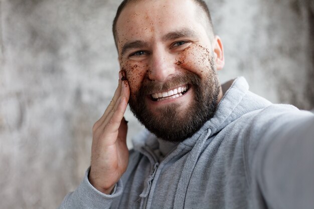 Photo sport, health, people, emotions, lifestyle concept - handsome man with three different face masks chocolate, cream and clay masks. photo of man with perfect skin. grooming himself