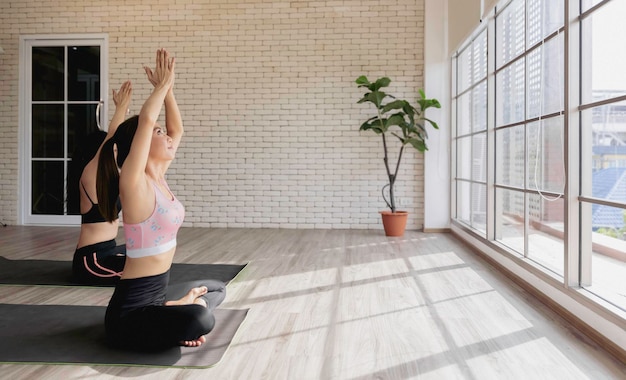 Sport healthy female in yoga suit sitting doing meditation in fitness studio