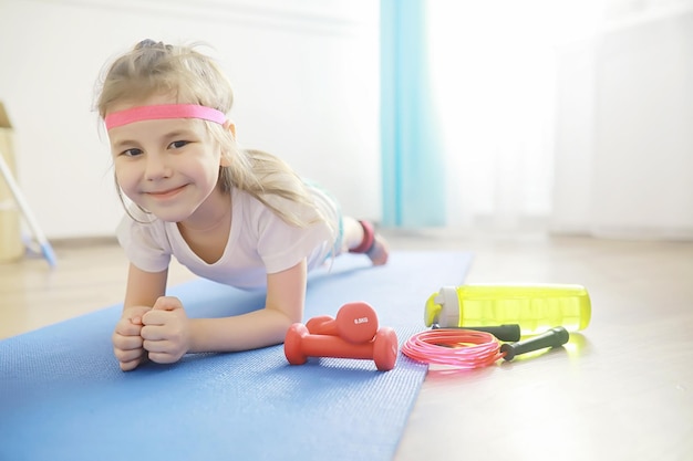 Foto sport e stile di vita sano. bambino che pratica sport a casa. manubrio per tappetino da yoga e corda per saltare. sfondo sportivo con il concetto di esercizi a casa.