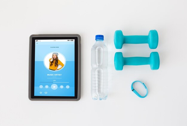 Photo sport, healthy lifestyle, fitness and technology  concept - close up of tablet pc computer with dumbbells, fitness tracker and water bottle over white background