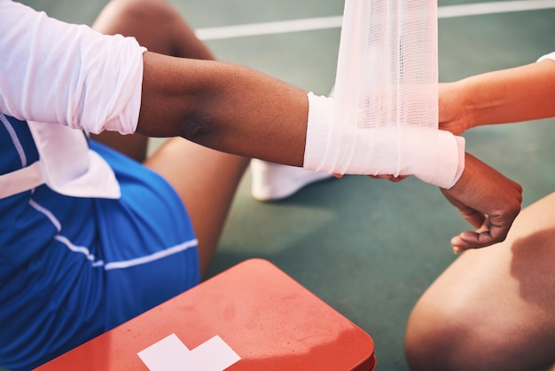 Sport injury bandage and first aid with wrist pain and help health and medic accident and people on netball court Medical emergency train and sports fitness and arm anatomy and muscle sprain