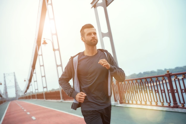 Sport is mijn leven zijaanzicht van een jonge en gelukkige bebaarde man in sportkleding