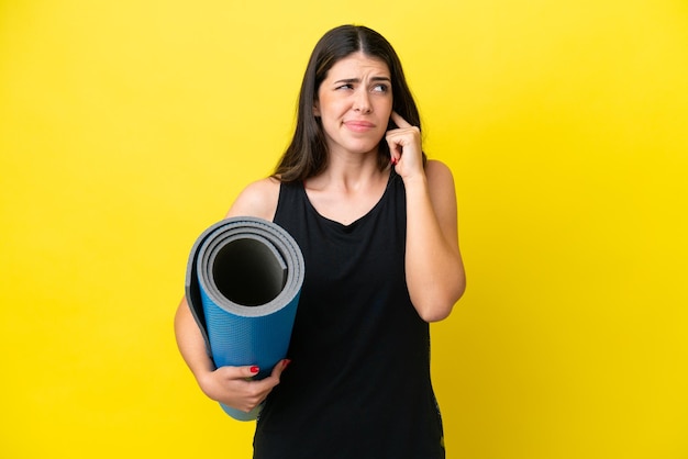 Sport Italian woman going to yoga classes isolated on yellow background frustrated and covering ears