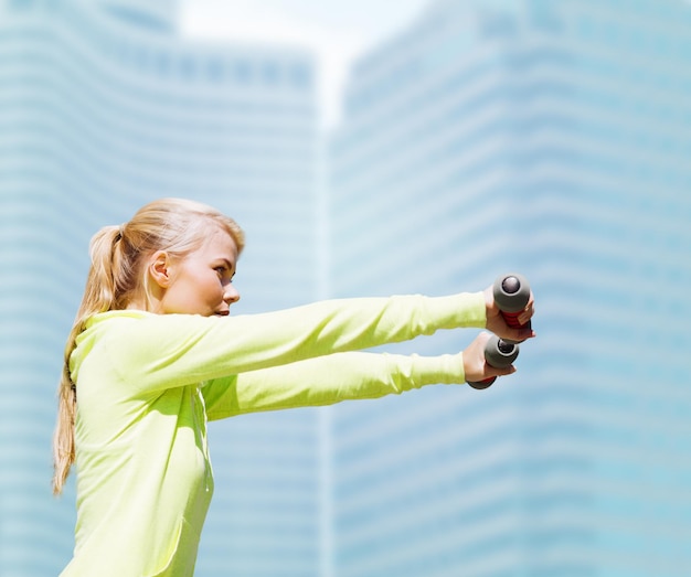 sport and lifestyle - young sporty woman with light dumbbells outdoors