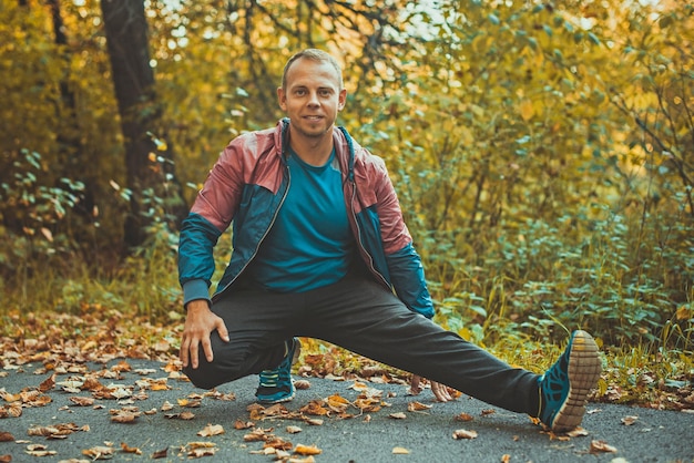 Sport man die zich uitstrekt in het park herfst oefeningen doen Fitness concepten