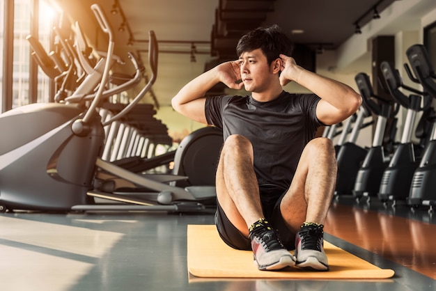 Sport man doet crunch of sit-up houding op yoga mat in fitness gym in condominium