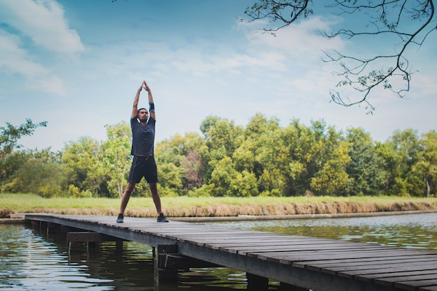 Sport man exercise and worm up on bridge with river 