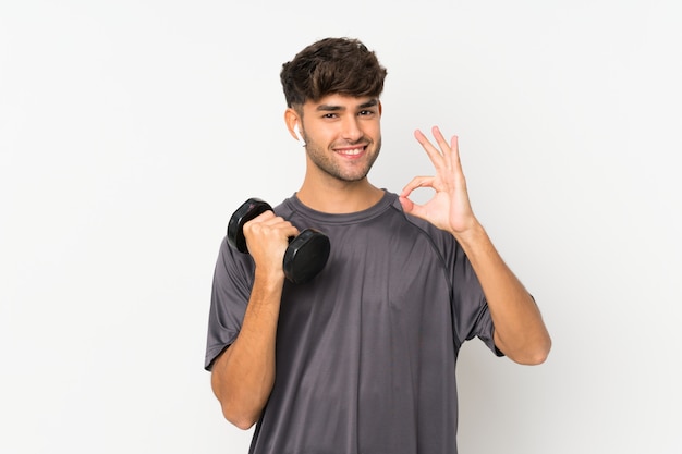 Sport man over isolated white wall showing ok sign with fingers