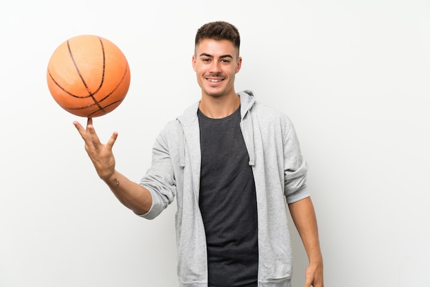 Sport man over isolated white wall with ball of basketball