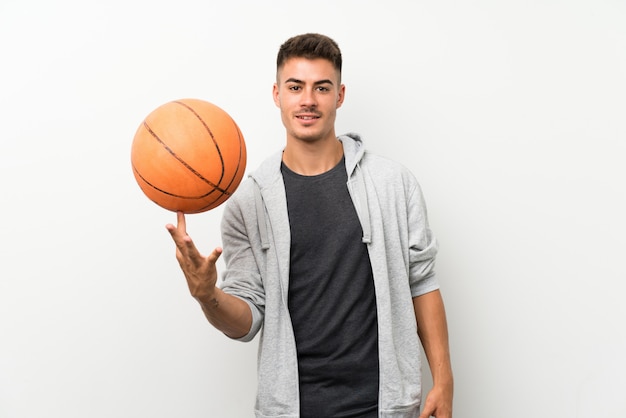 Foto metta in mostra l'uomo sopra la parete bianca isolata con la palla di pallacanestro