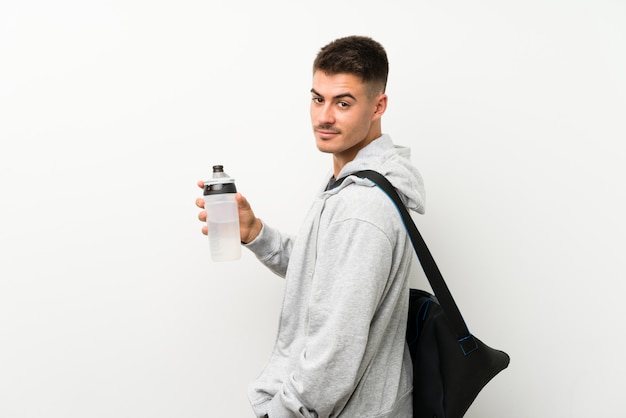 Sport man over isolated white wall with a bottle of water