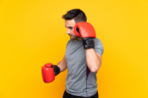 Sport man over isolated yellow wall with boxing gloves