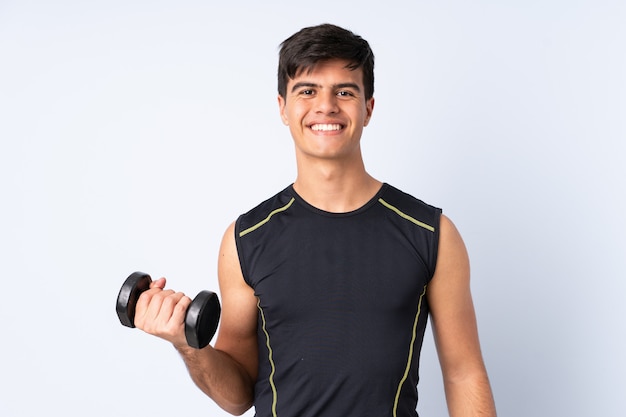 Sport man making weightlifting over blue wall smiling a lot