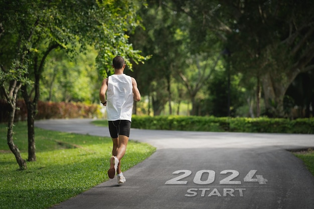 Sport man running at park garden start into the new year 2024 start up of runner woman running on road park nature go to goal of success people running as part of number 2024 sport health care