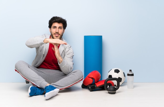 Sport man sitting on the floor making time out gesture