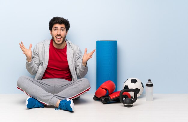 Sport man sitting on the floor with shocked facial expression