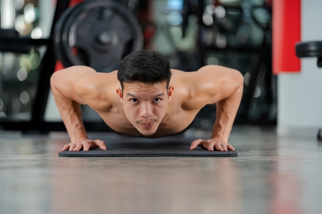 Photo sport man training doing push-ups exercise in fitness gym