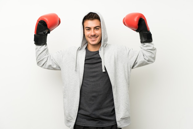 Спортивный человек над белой стеной с боксерскими перчатками