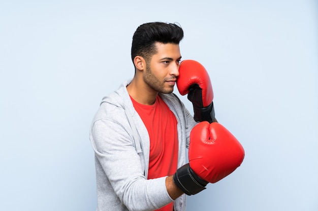 Спортивный человек с боксерскими перчатками над синей стеной