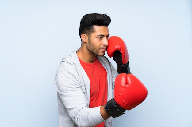 Sport man with boxing gloves over isolated blue wall