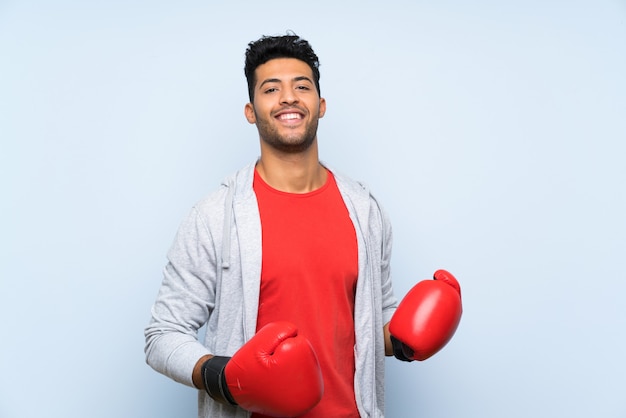 Sport man with boxing gloves over isolated blue wall