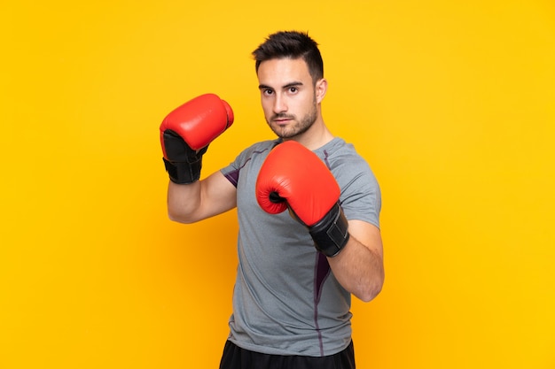 Sport man over yellow wall with boxing gloves