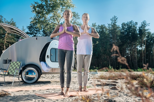 Sport mat. Slim and fit athletic couple standing on sport mat while meditating in the morning together