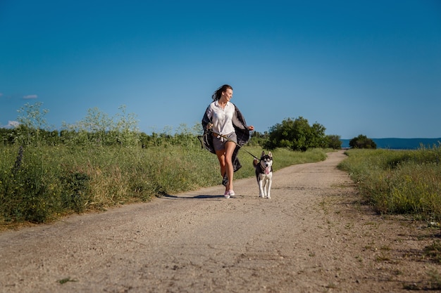 Sport meisje loopt met een hond de Siberische Husky op de weg