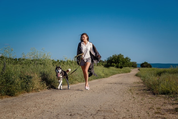 Sport meisje loopt met een hond de Siberische Husky op de weg