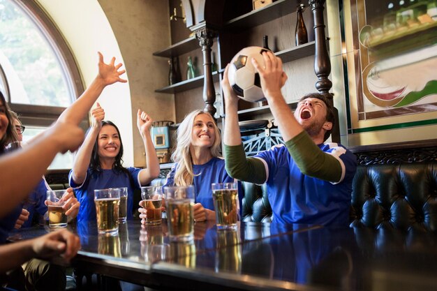 Foto sport, mensen, vrije tijd, vriendschap en entertainment concept - gelukkige voetbalfans of vrienden die bier drinken en de overwinning vieren in de bar of pub