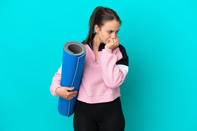 Sport Oekraïense vrouw die naar yogalessen gaat terwijl ze een mat vasthoudt en twijfelt