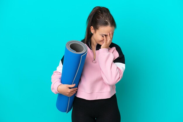 Sport Oekraïense vrouw die naar yogalessen gaat terwijl ze een mat vasthoudt met een vermoeide en zieke uitdrukking