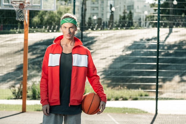 스포츠 복장. 농구를하러 오는 동안 스포츠 재킷을 입고 즐거운 젊은 남자